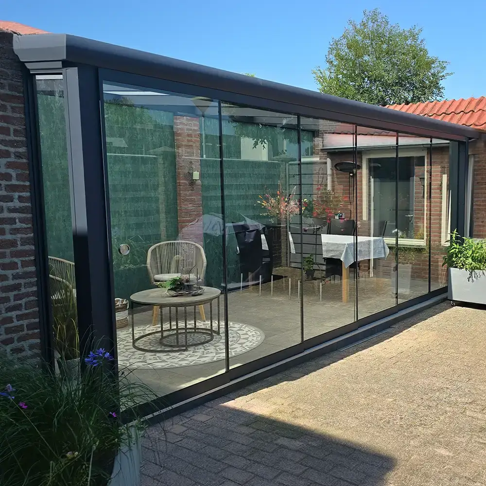 Moderne veranda met glazen dak en tuinmeubilair.