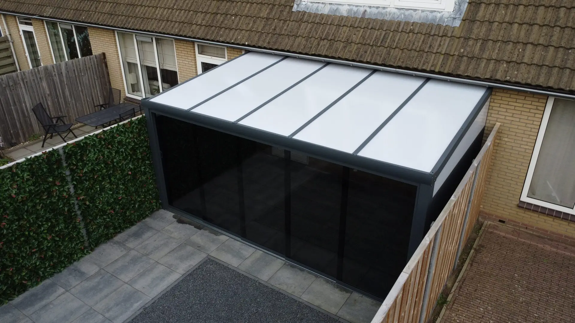 Polycarbonaat veranda in een moderne achtertuin met tuinmeubelen.